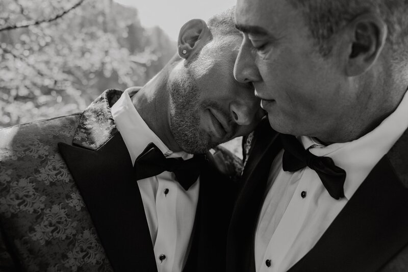 Close up of a gay couple holding each other in an intimate moment during their wedding day