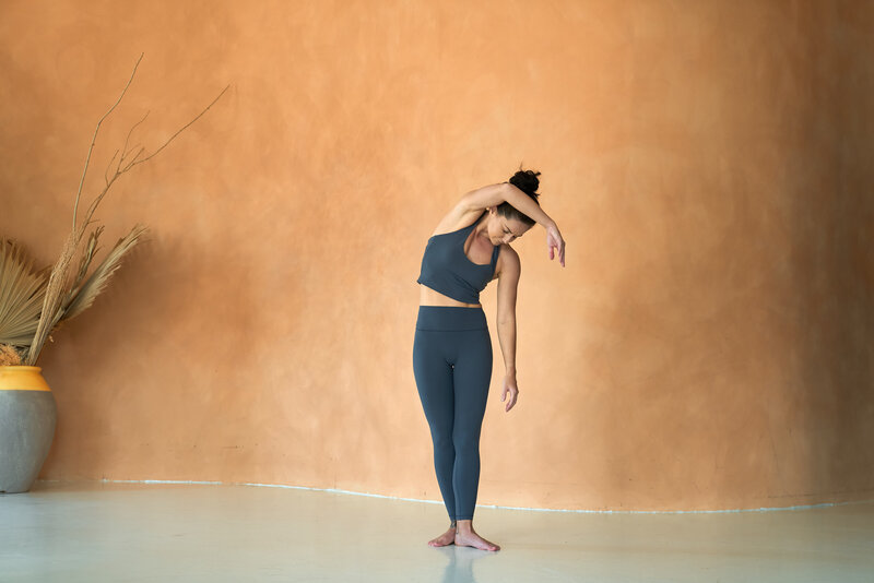 Sarah in a tree pose against a clear sky, balancing on the sunlit desert sand, highlighting focus and poise for creative yoga sequence instruction.