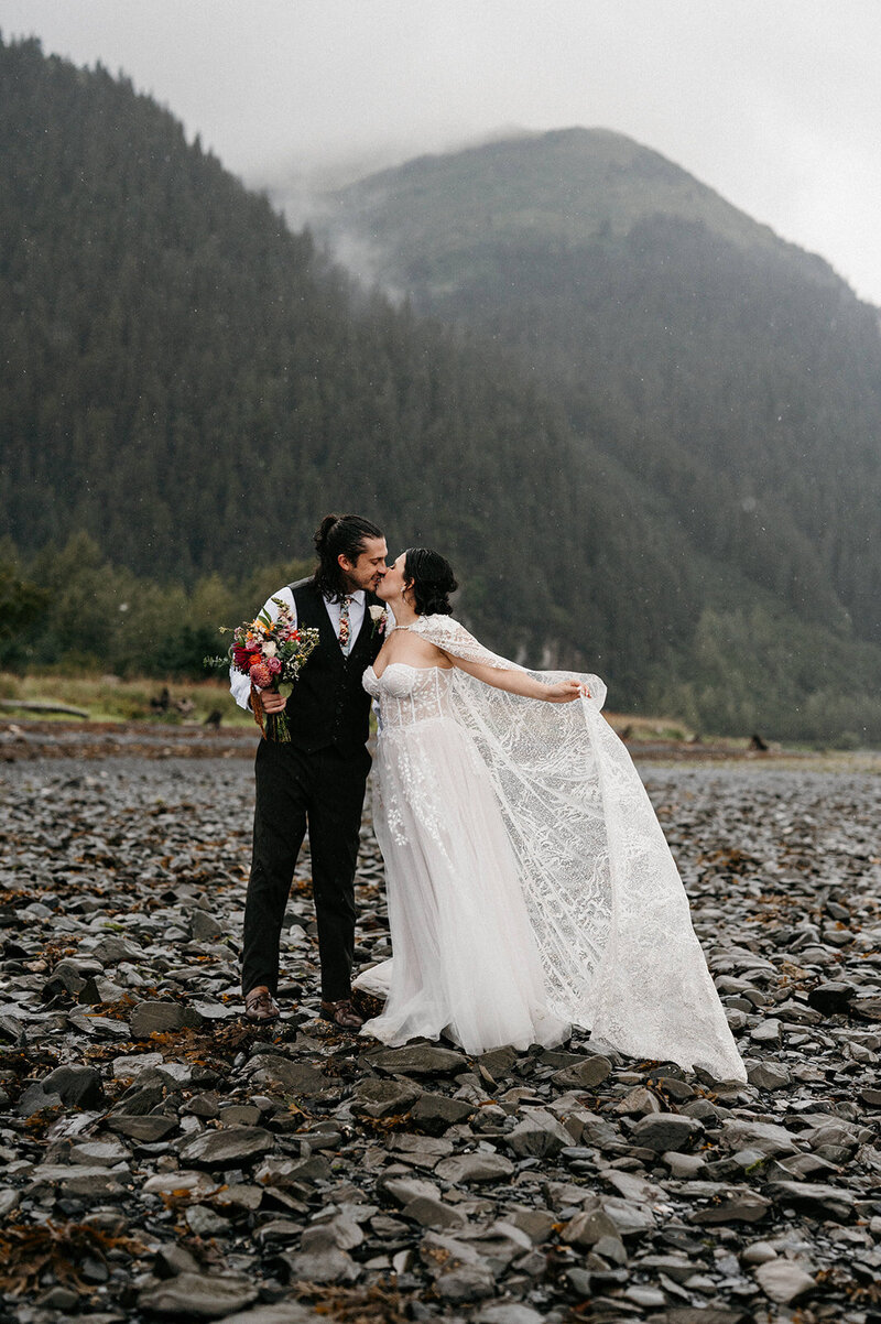 Man and woman hold onto each other beneath Exit Glacier in Seward.