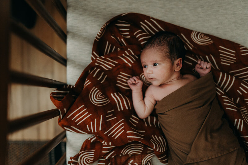 baby in his crib laying on a swaddle