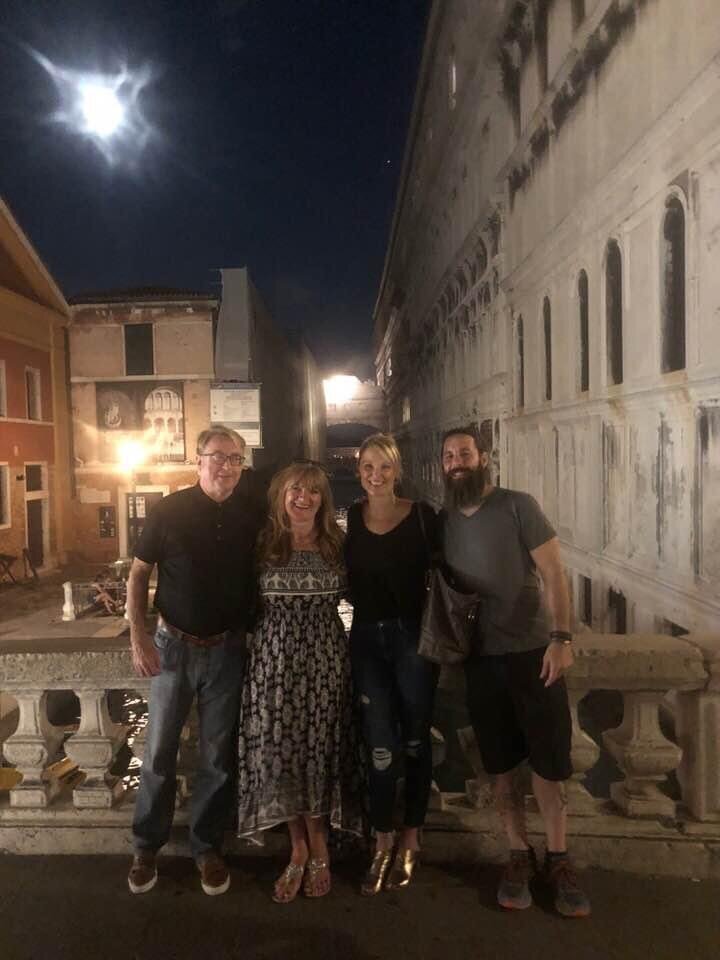 Two couples on Ponte de Canonica footbridge overlooking Bridge of Sighs, Doges Palace at night
