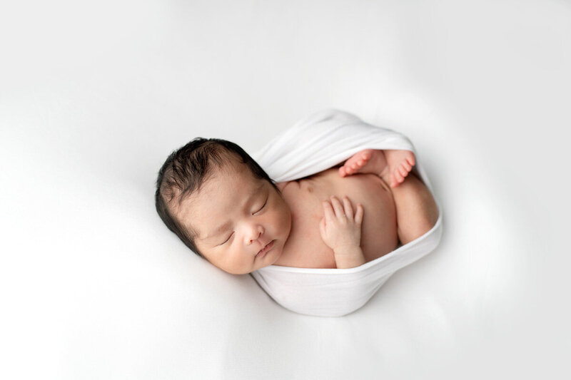 Newborn session with baby in white swaddle