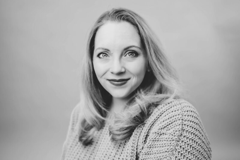 A monochrome portrait captured by a photographer of a smiling woman with long hair wearing a knitted sweater.