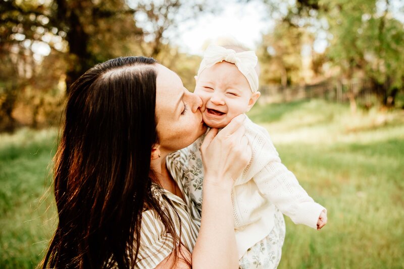 mom gives baby kisses on the cheek