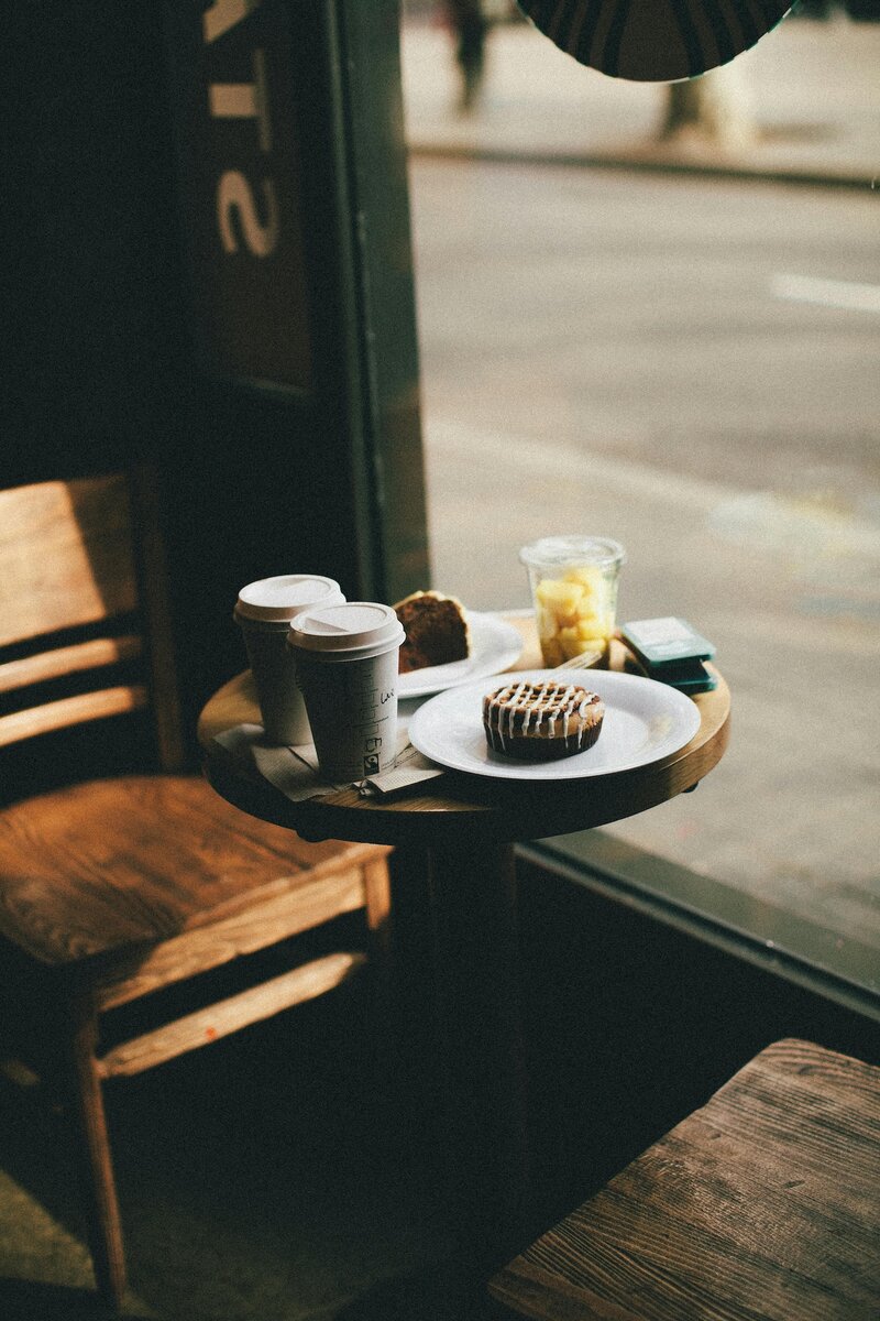 Two cups of coffee, fruit and two pastries sitting on a cafe table
