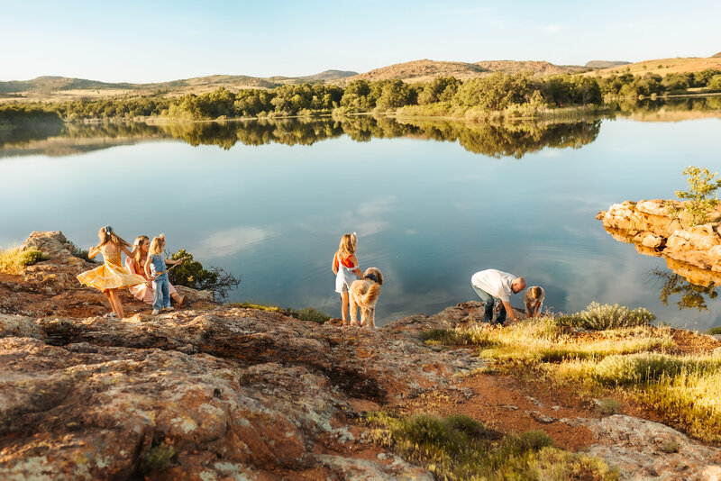Family of five and their dog play near the blue water during their family session with Kansas City Lifestyle Photographers.