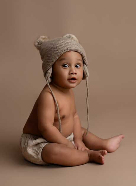 Baby milestone photoshoot of boy sitting up wearing a bear hat. Photo taken by Jenni Nikki Photography in Atlanta GA.