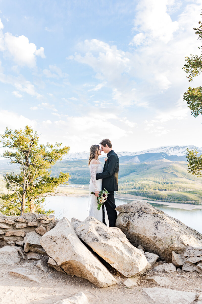 Couple in wedding attire stand on the side of mountain in Colorado elopement at Sapphire Pointe.