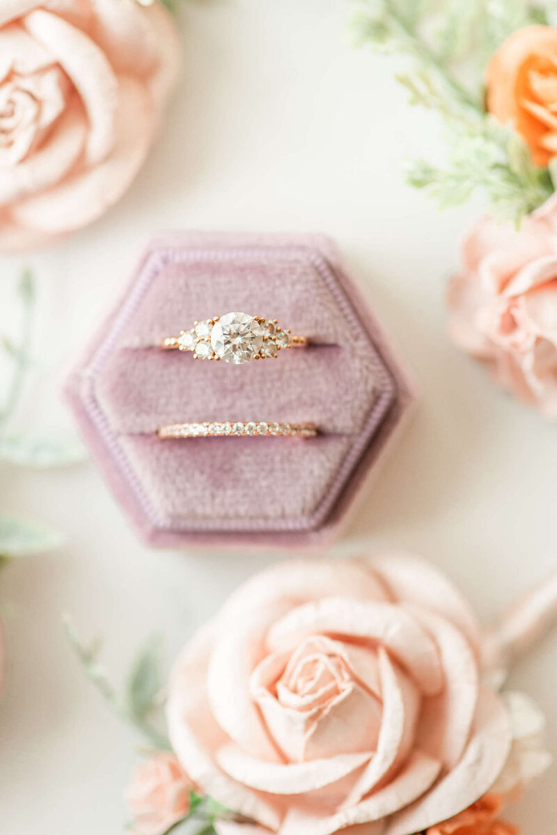 Engagement and wedding ring in a pink ring box, with pink flowers around it, staged for a wedding photo in Madison, WI