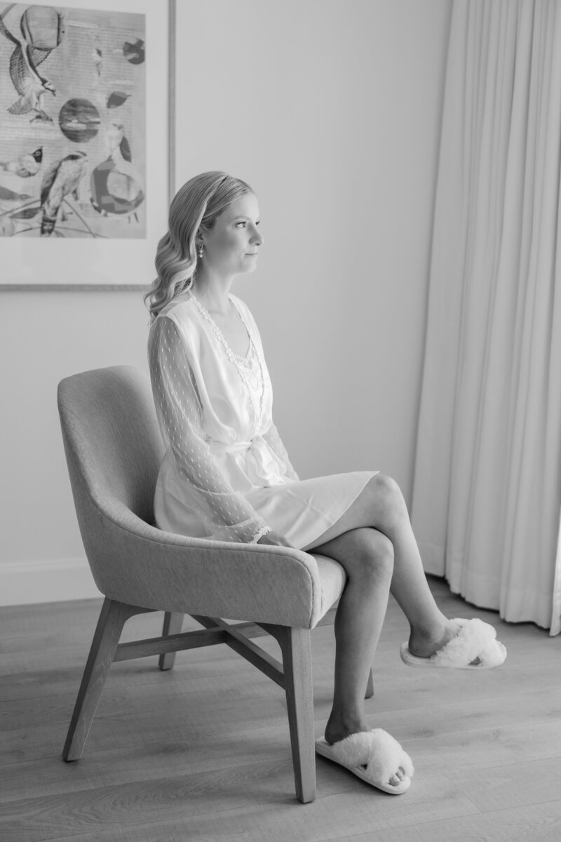 Bride looking out the window in a black and white photo at the Alfond Inn.