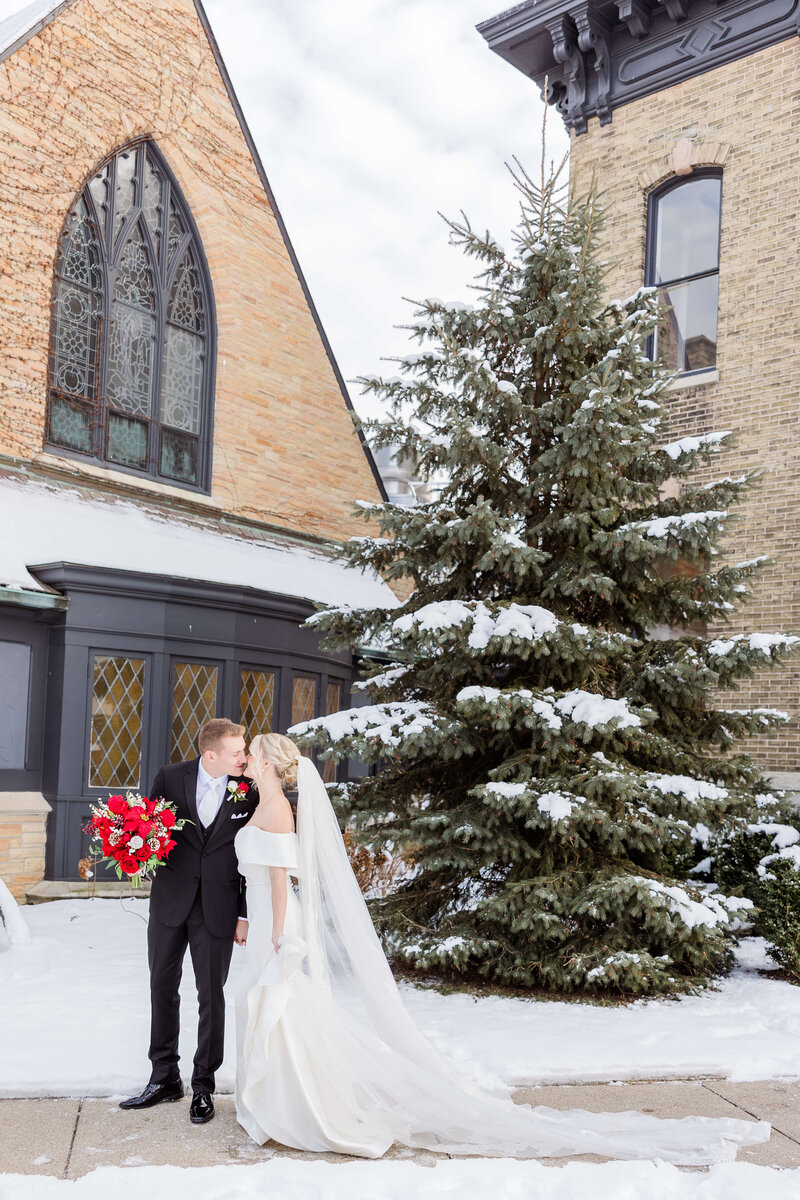 Winter bride and groom with snow kissing.