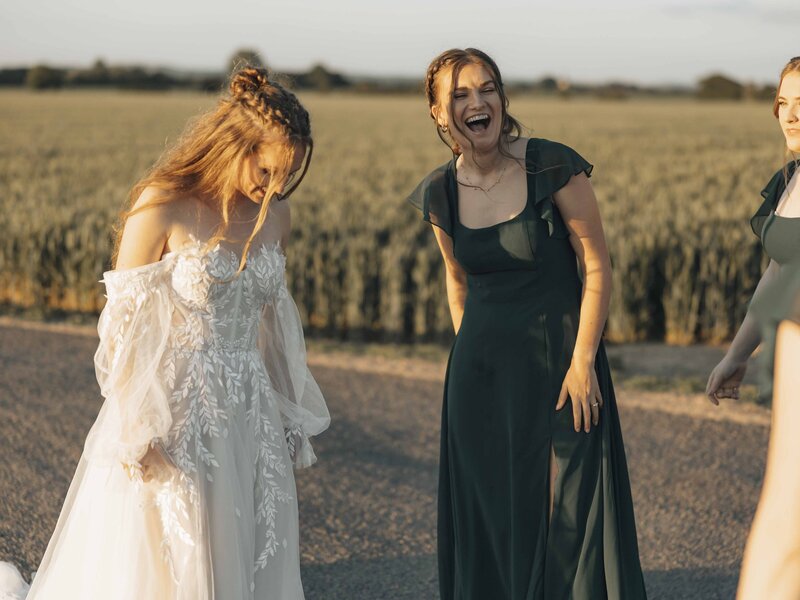 Bridesmaid laughing with bride at sunset