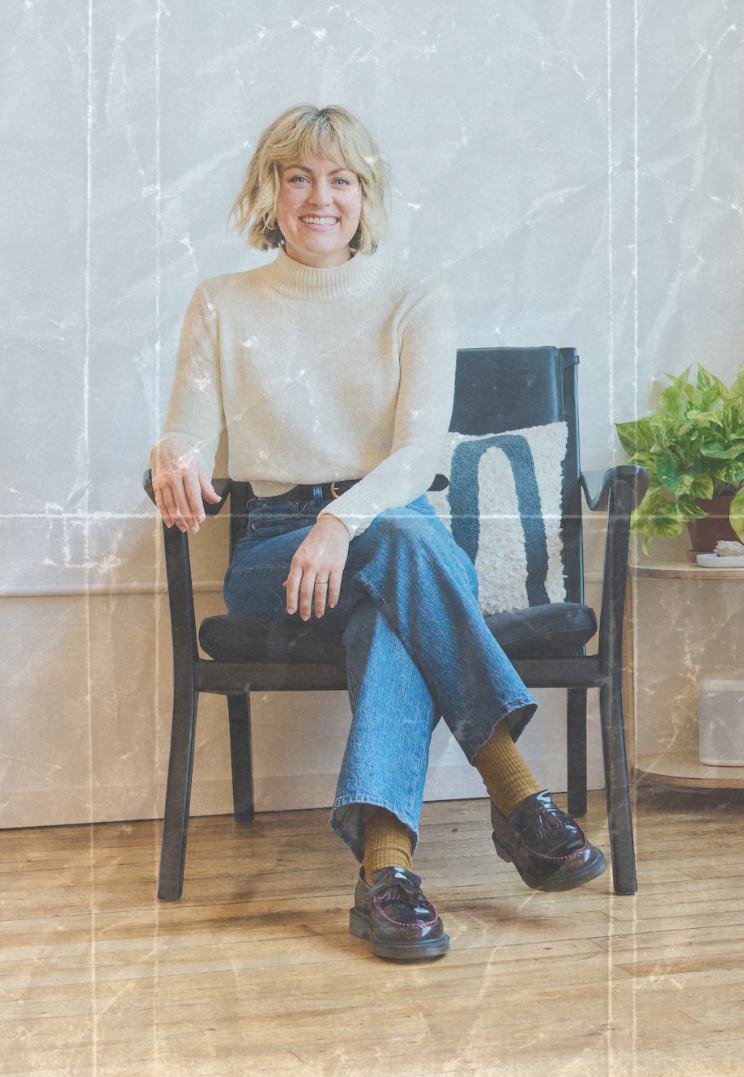 Greenpoint, NY Psychiatrist, Laura Temple, sits casually in jeans, loafers and a cream-colored turtle neck smiling for the camera. Photo has a nostalgic film effect overlay.