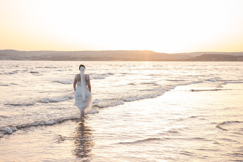Devon Bride walks in the sea at sunset