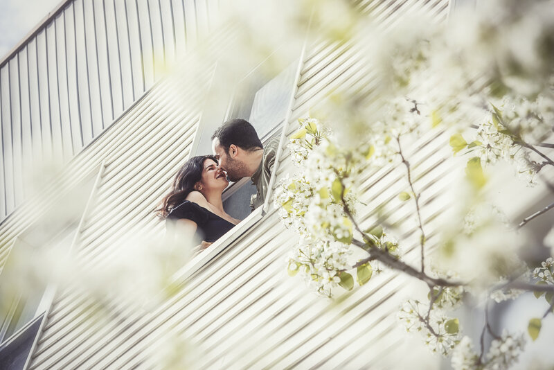 Image from below of a couple leaning out a window about to kiss