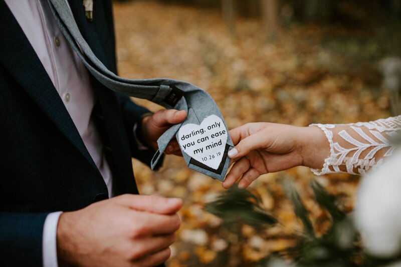 hand holding the back of the grooms tie with a message on it