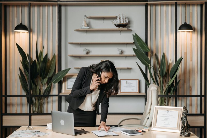 Woman on the phone sorting through paperwork at desk