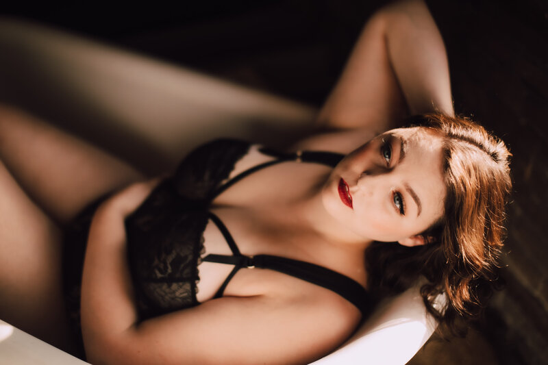 Woman sits in bathtub during session with Appleton boudoir photographer