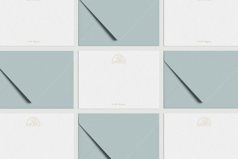 a mockup showing a gold logo on white stationery with blue envelopes