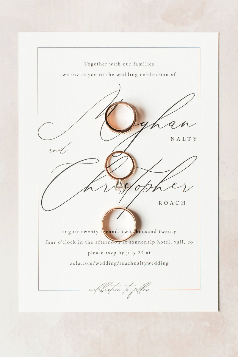 Detail photograph of three wedding rings laying on a wedding invitation.