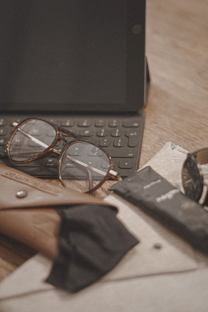 Laptop, paper and glasses representing working on set as a film producer. 