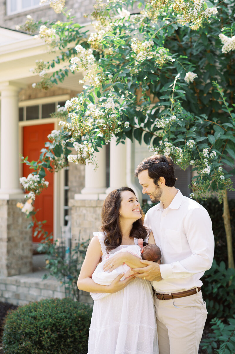 Mother and father smiling outside with newborn