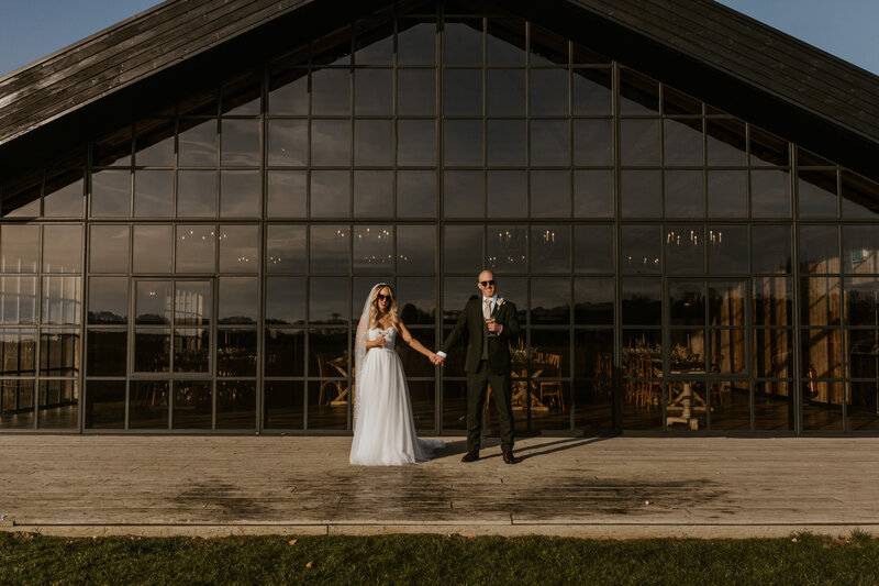 black and white image of a couple relaxing and walking while kissing in the winter gardens at Foxtail Barns