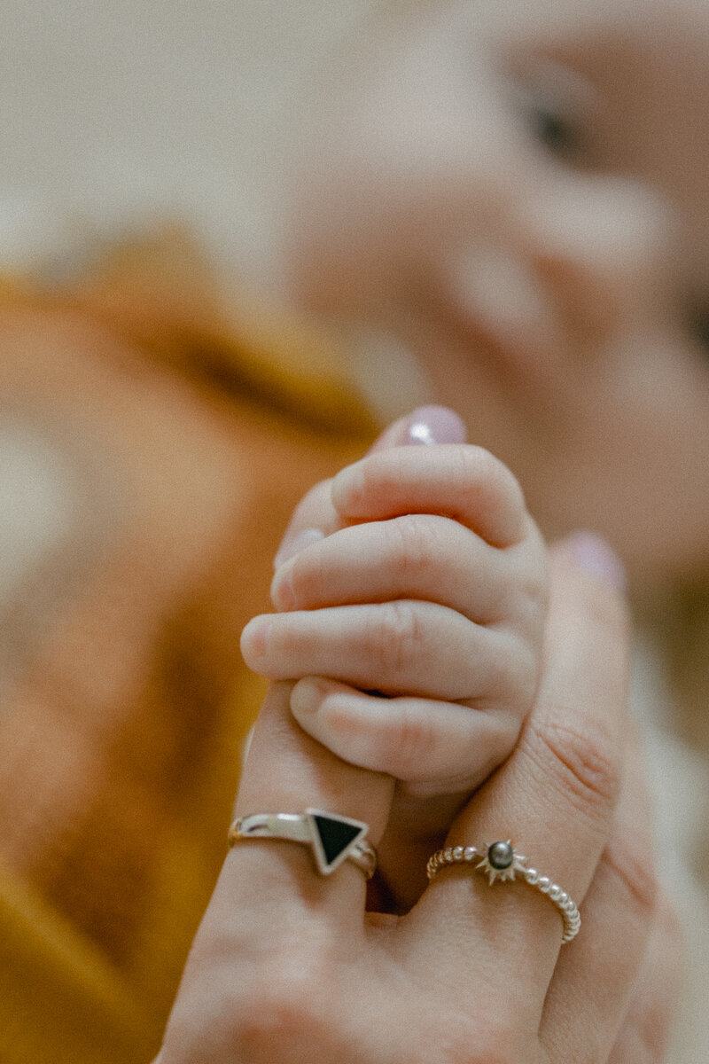 A Homely photo session by Cindy Young Photography taken of a baby girl gripping her mother's index finger.