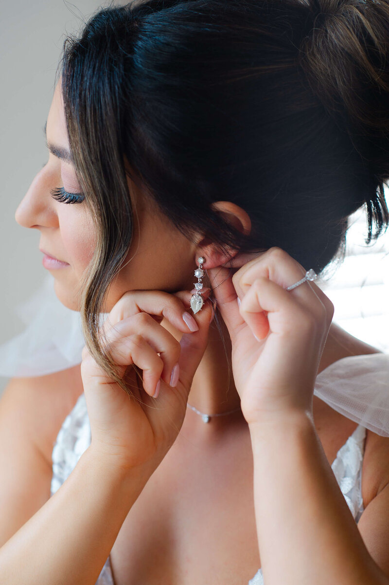 Ottawa wedding photos of a bride putting on her earrings as she gets ready.  Captured by JEMMAN Photography