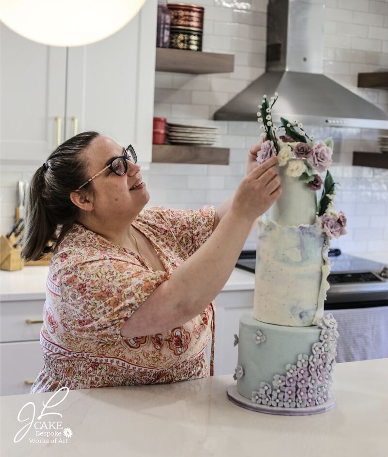 JL Cake designer adjusting sugar flowers on luxury wedding cake