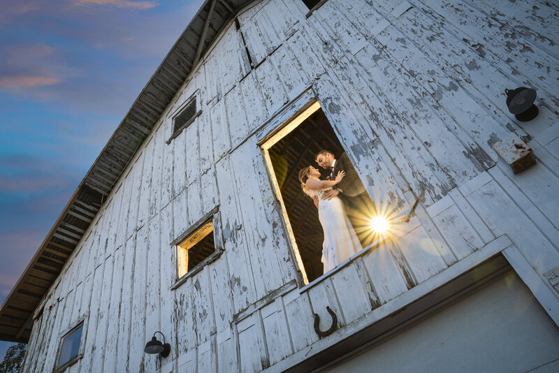 Wedding couple posing by an old barn.