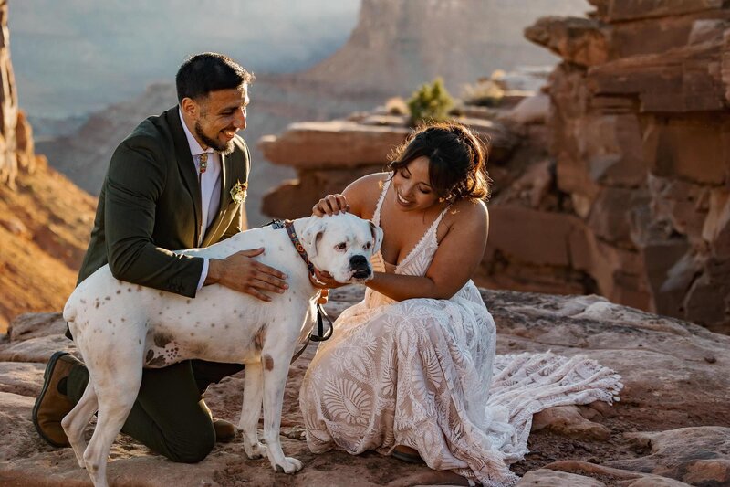 A couple pets their dog Pongo as the sunsets on their Moab Elopement