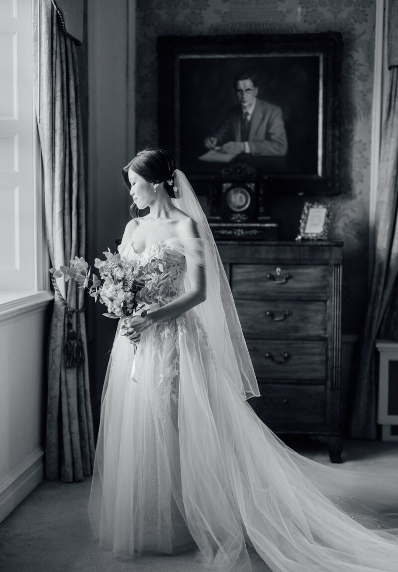 black-and-white-image-of-bride-at-destination-wedding-waterford-castle-bride-with-vintage-lace-veil-and-white-bouquet-with-groom