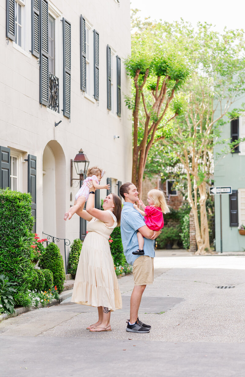 Mom and dad holding their toddler girls in historical downtown Charleston