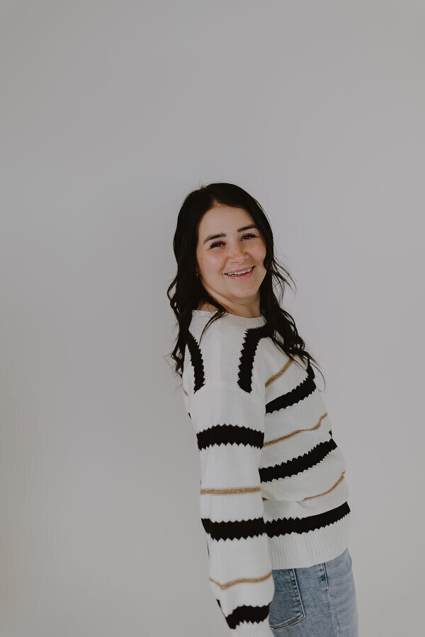 Smiling for a photo in an all white studio in Idaho Falls, ID, Britt poses for a portrait.