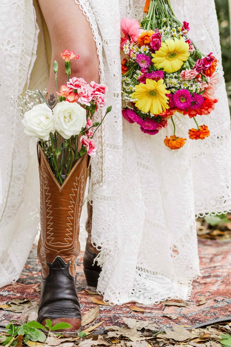 Closeup of bride's bouquet held down by her boot which is also filled with flowers