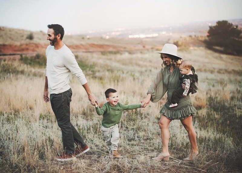 Framed portrait of three sisters holding hands wearing flower crowns in a northern colorado field.