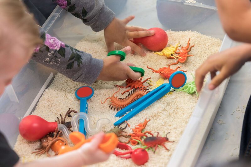 overhead shot of child playing with colorful toys in sand