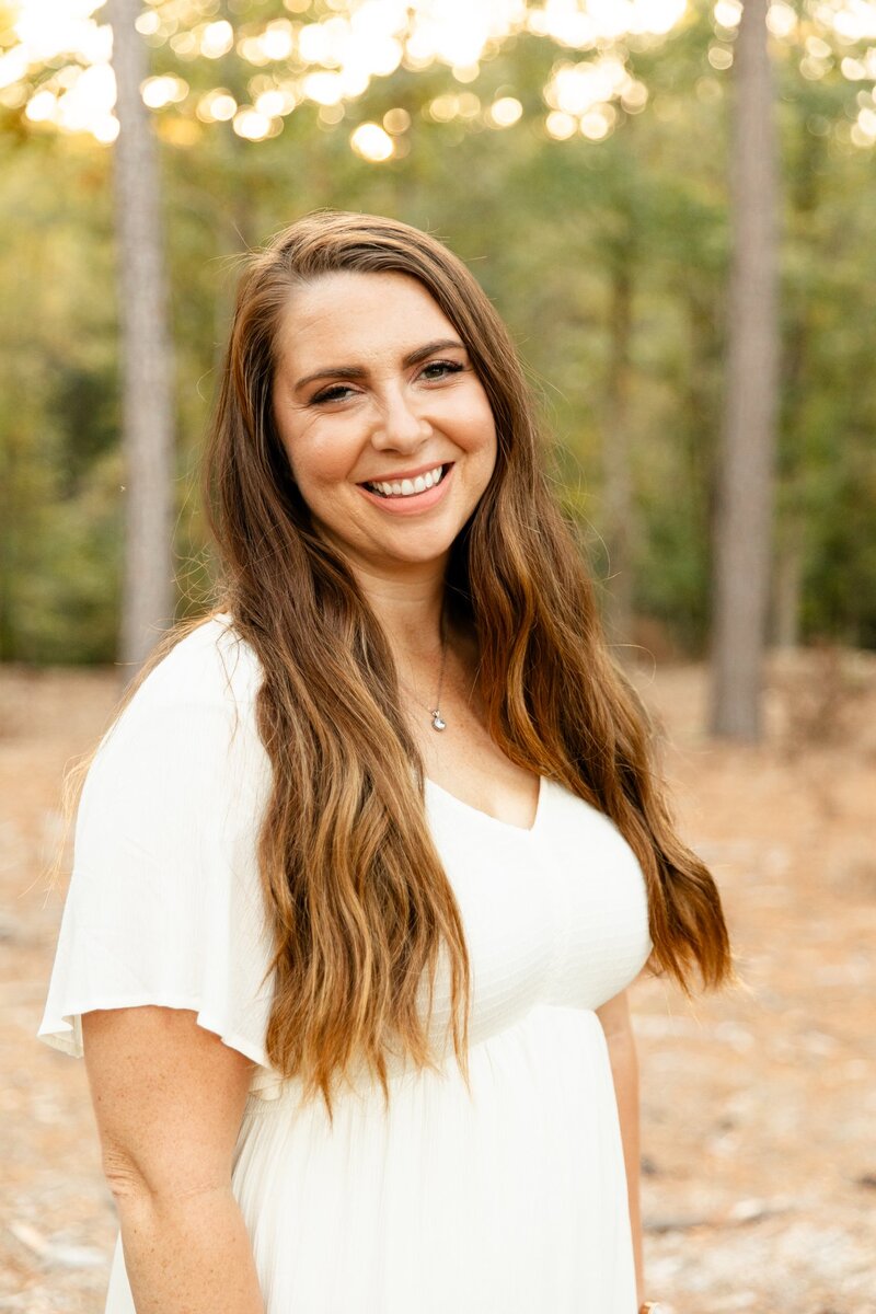 Woman smiling looking at the camera with trees in the background