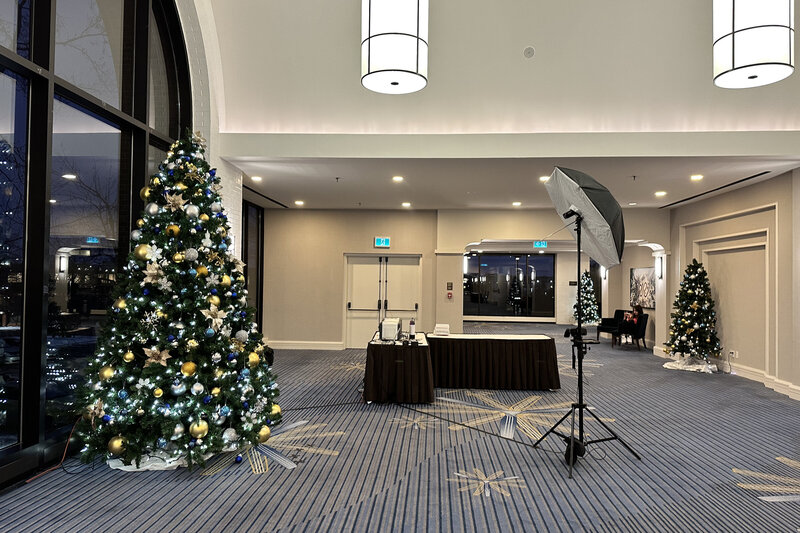 An onsite printing table displaying printed event photos alongside a photographer capturing professional portraits on a red carpet with a festive backdrop