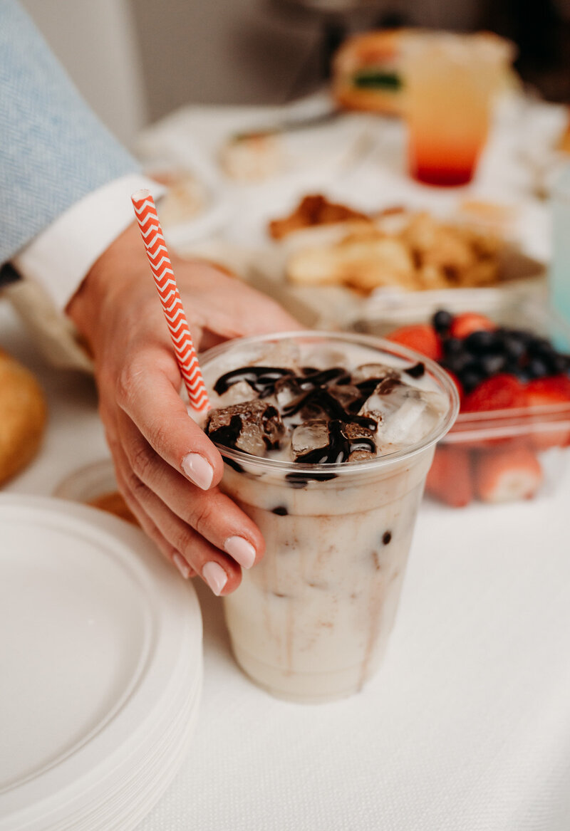 woman holding iced chocolate drink with a red and white pinstripe straw