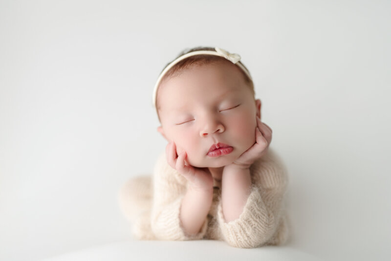  Fine-art newborn portrait of baby girl in froggy pose, styled in cream tones and photographed in Paris, Ontario.
