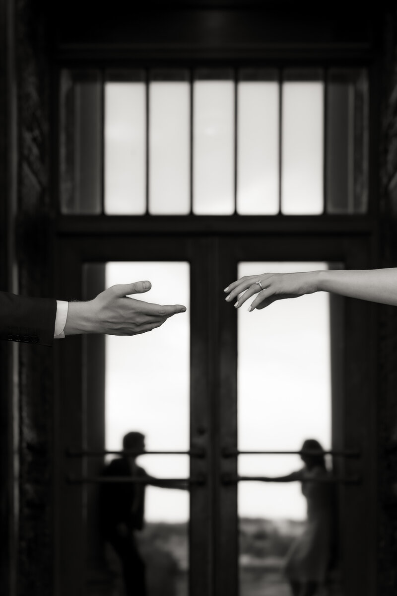 The following image shows a future bride and groom reaching for one another’s hands in an artistic black and white, timeless photograph. This was photographed in front of the Nelson-Atkins in Kansas City, Missouri.