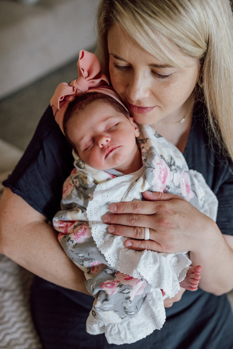 A mother sitting in her home with her baby swaddled in Hillsboro, Missouri. 
