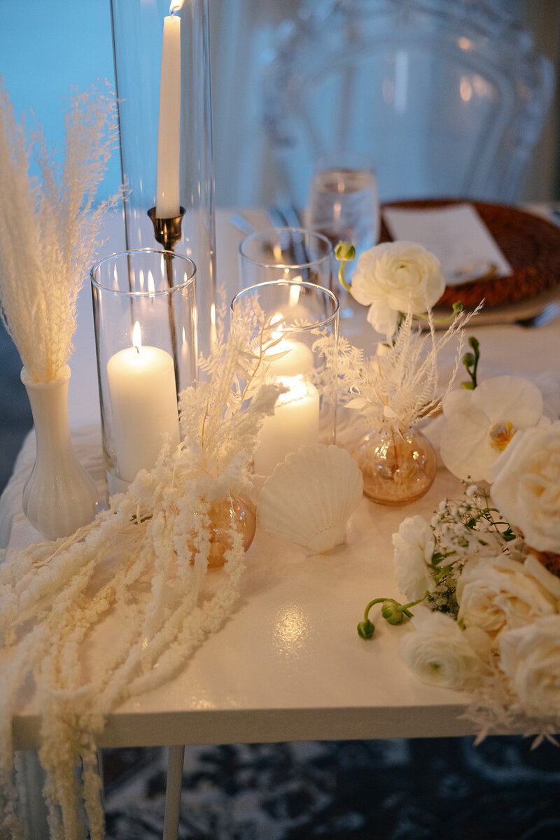 Modern white wedding tablescape with candles and minimalist floral arrangements, styled by St. Augustine wedding planners The Eventful Gals.