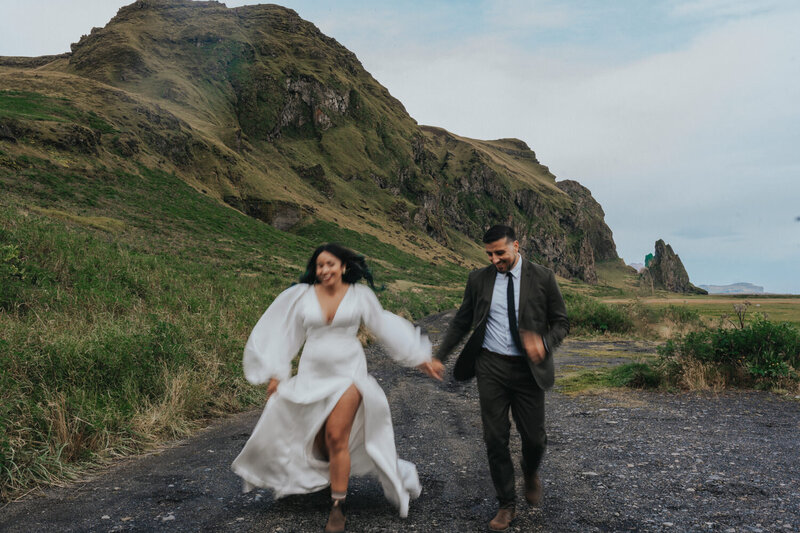 A couple runs together down a gravel path in Iceland