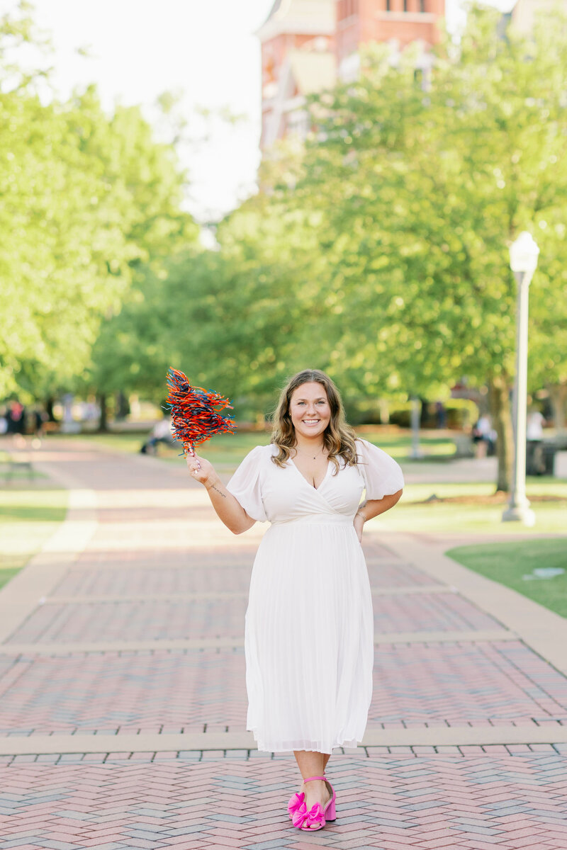 Auburn graduate with a pom pom on campus