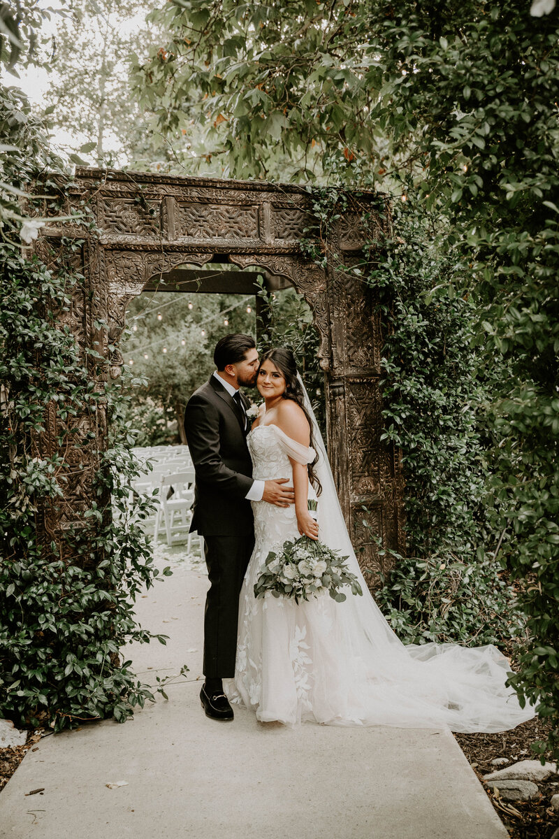 bride and groom posing under arch