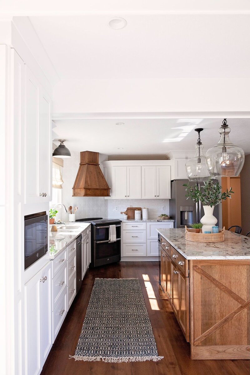 Modern kitchen with large airy light fixtures, white cabinets and a dark island.