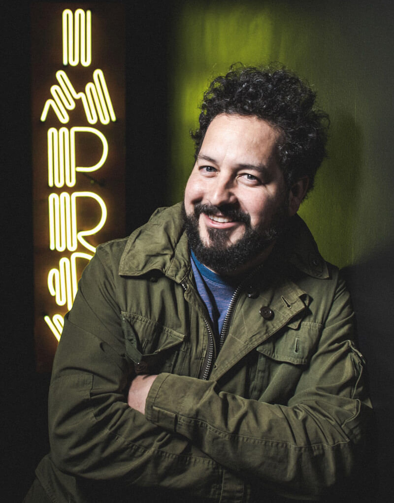 Photo of comedian, Ahmed Bharoocha, in a green jacket